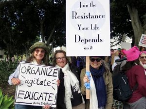 3 women holding signs that say Organize, Agitate, Educate and Join the Resistance Your life Depends on It